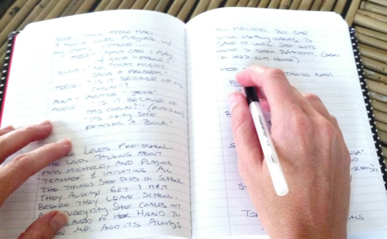 A hand holds a pen over a full page of lined writing paper in a notebook.