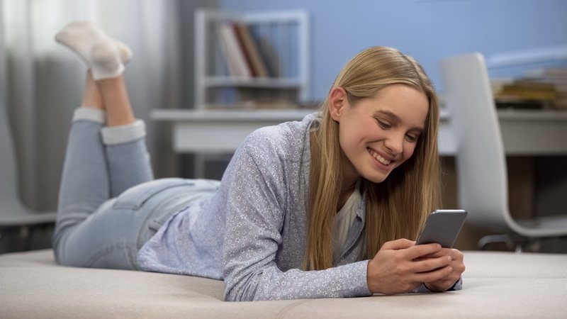 Happy girl typing message to friend in social network, first love in teen age